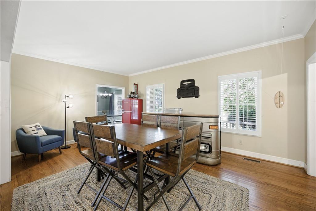 Furnished dining room with a wooden table, blue armchair, red refrigerator, and stainless steel stove.