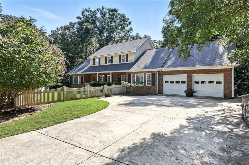 Two-story brick-and-siding home with a double garage, broad driveway, and fenced front lawn.