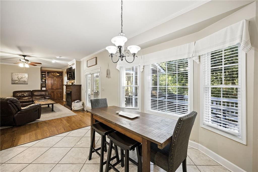 Dining and living room with a wooden table, large windows, tiled floor, and leather seating area.