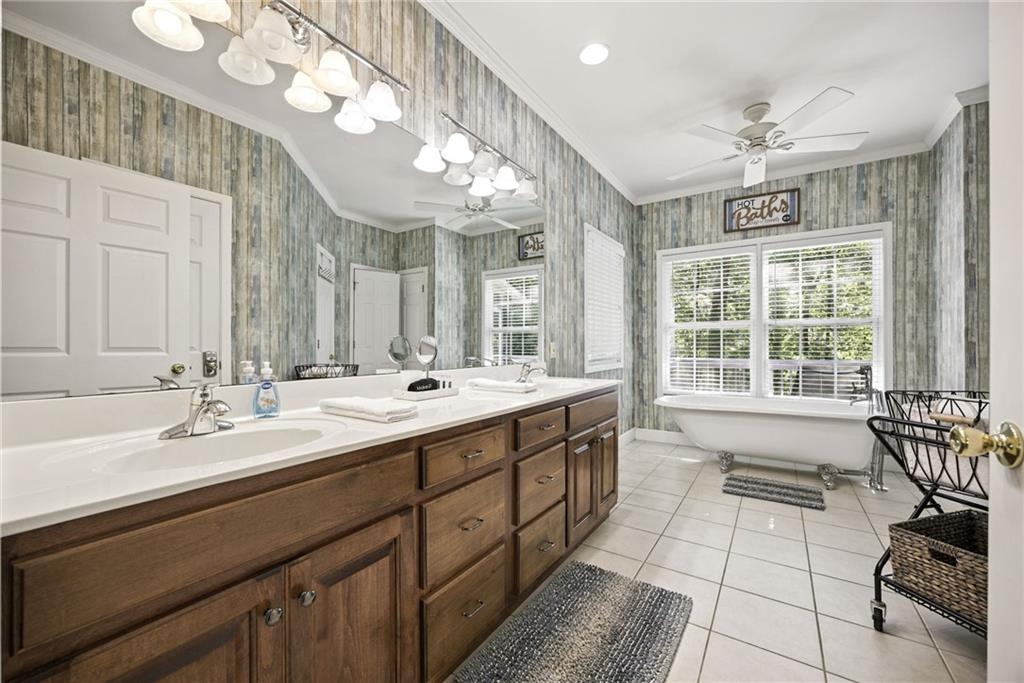 Bathroom with a long double vanity and a clawfoot tub beneath a wide window.