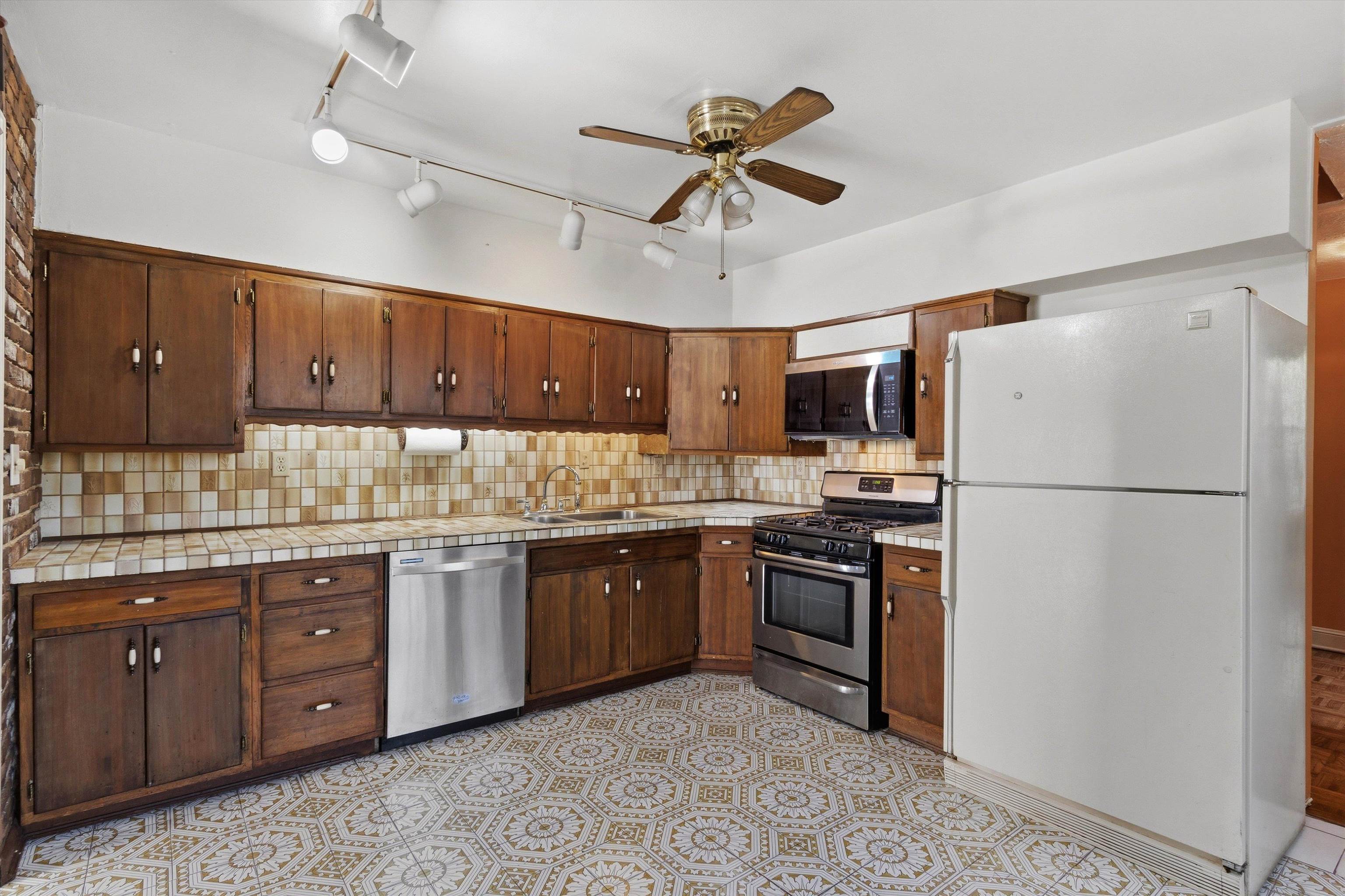 Kitchen with dark wood cabinets, patterned tile floors, and a large white refrigerator.
