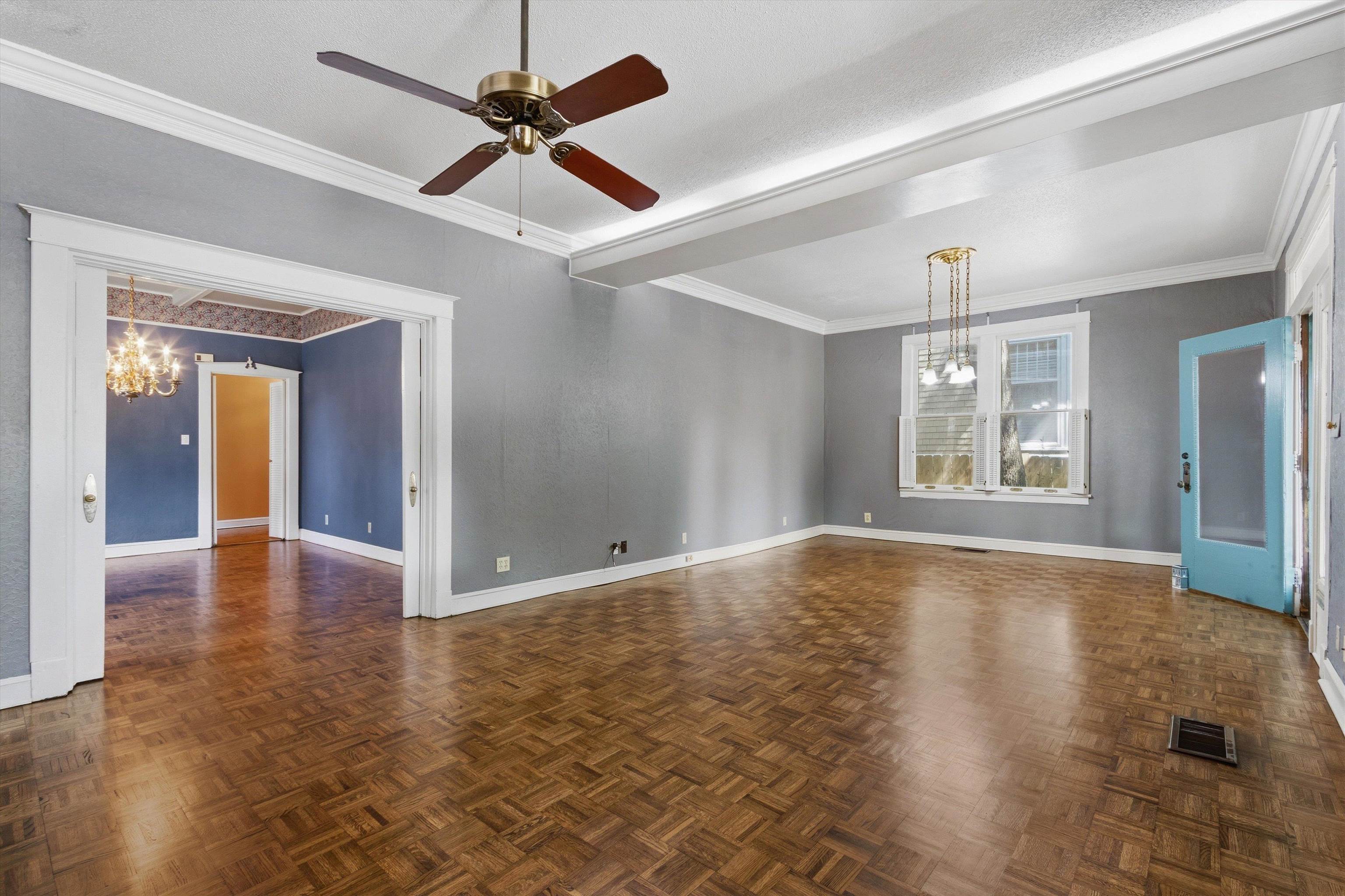 Vacant living room with parquet floors, gray walls, and a turquoise door.