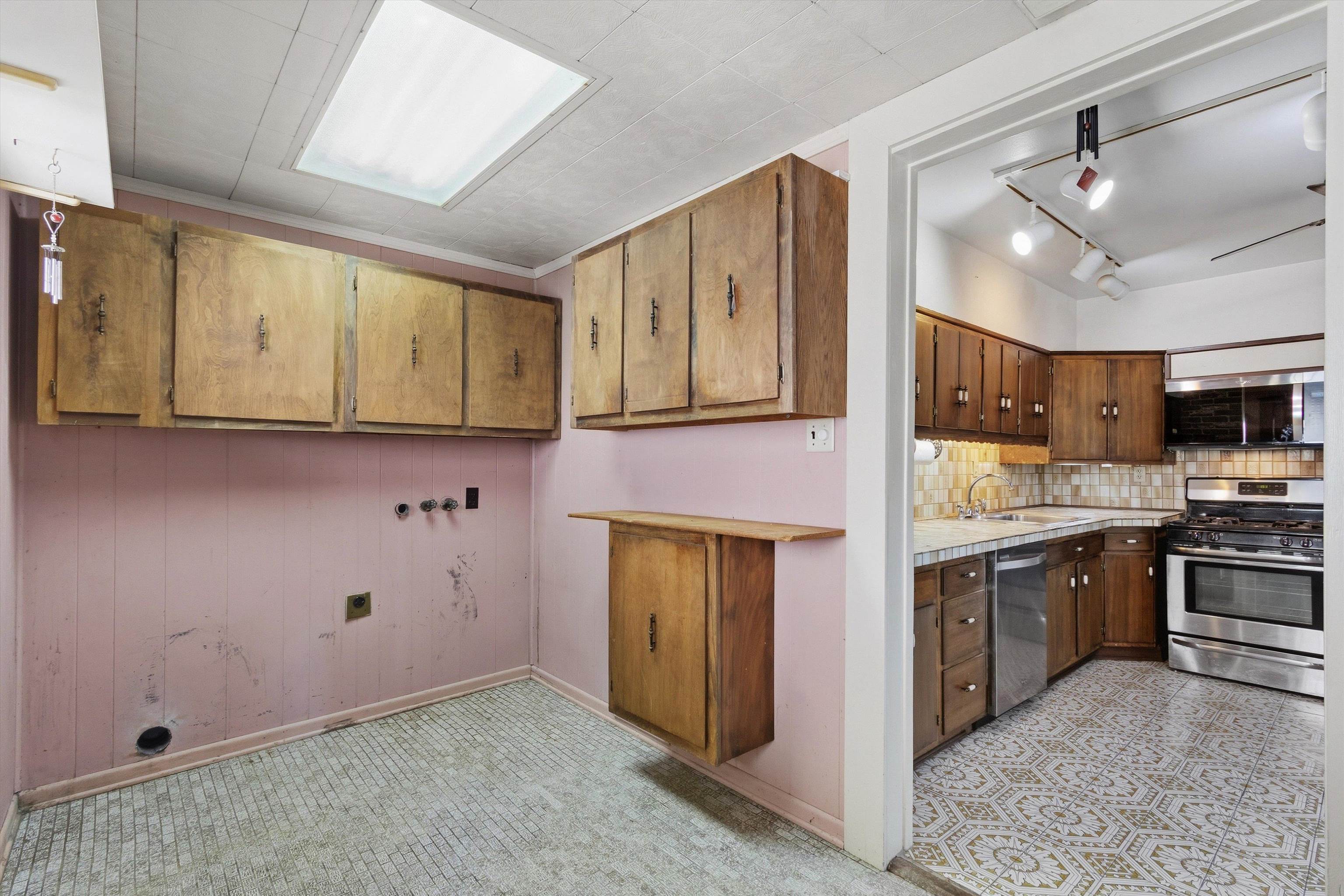 Kitchen with adjoining utility area, wood cabinets, patterned tile, and exposed appliance hookups.
