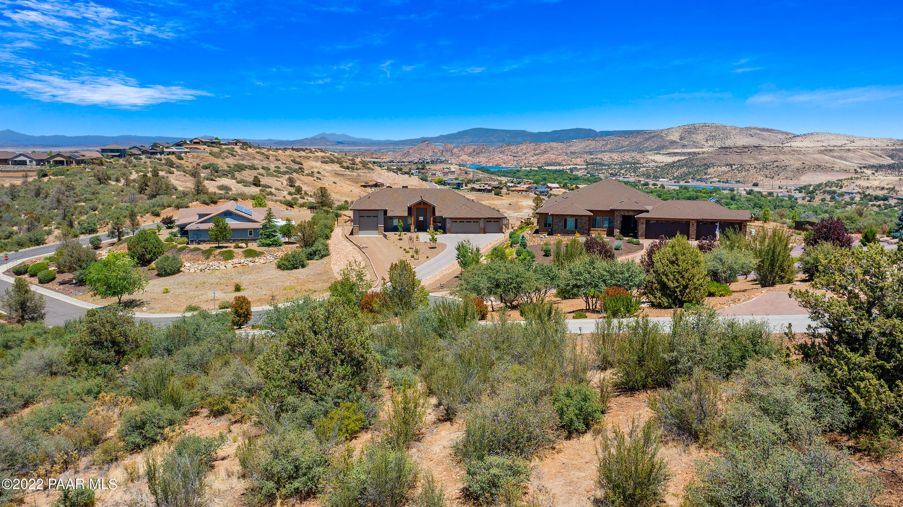 Aerial view of hillside homes with desert landscaping and distant mountain views.