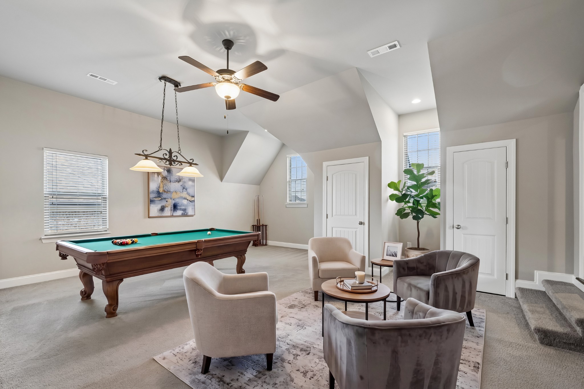 Furnished game room with a pool table, lounge chairs, and a high angled ceiling.