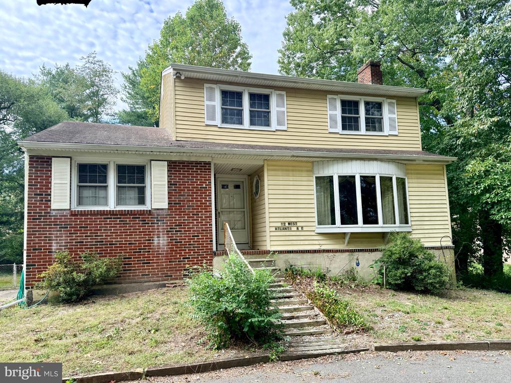 Two-story home with brick and yellow siding, a bay window, and concrete front steps.