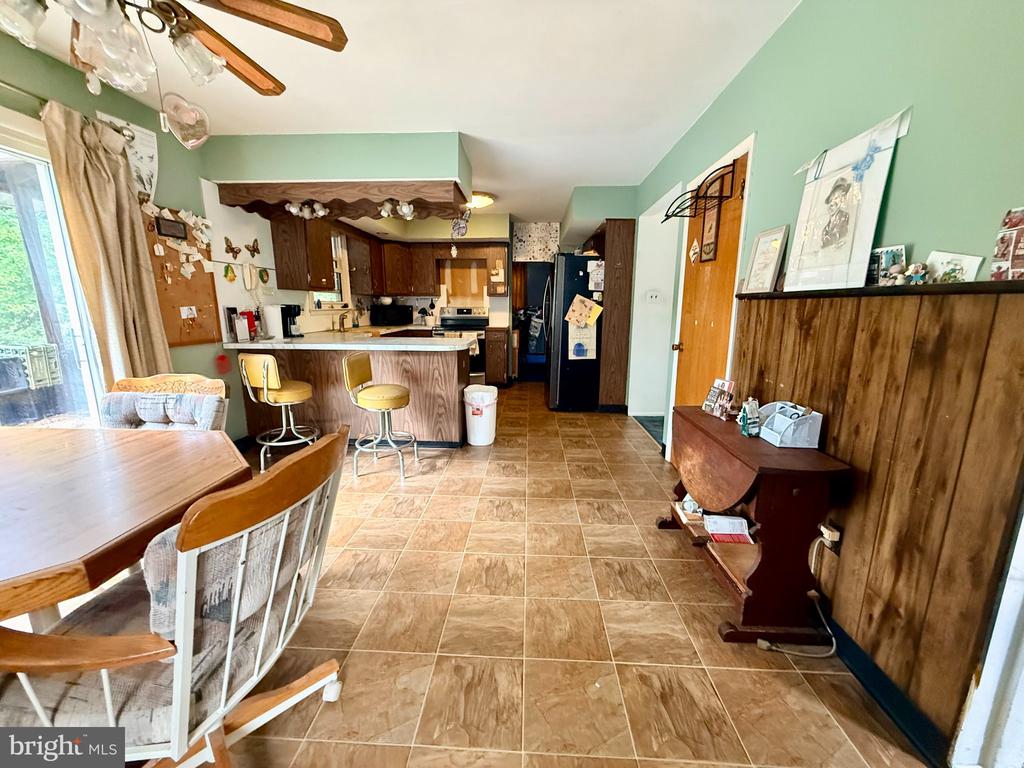 Kitchen and dining area with a breakfast bar, wood cabinets, and brown tile flooring.