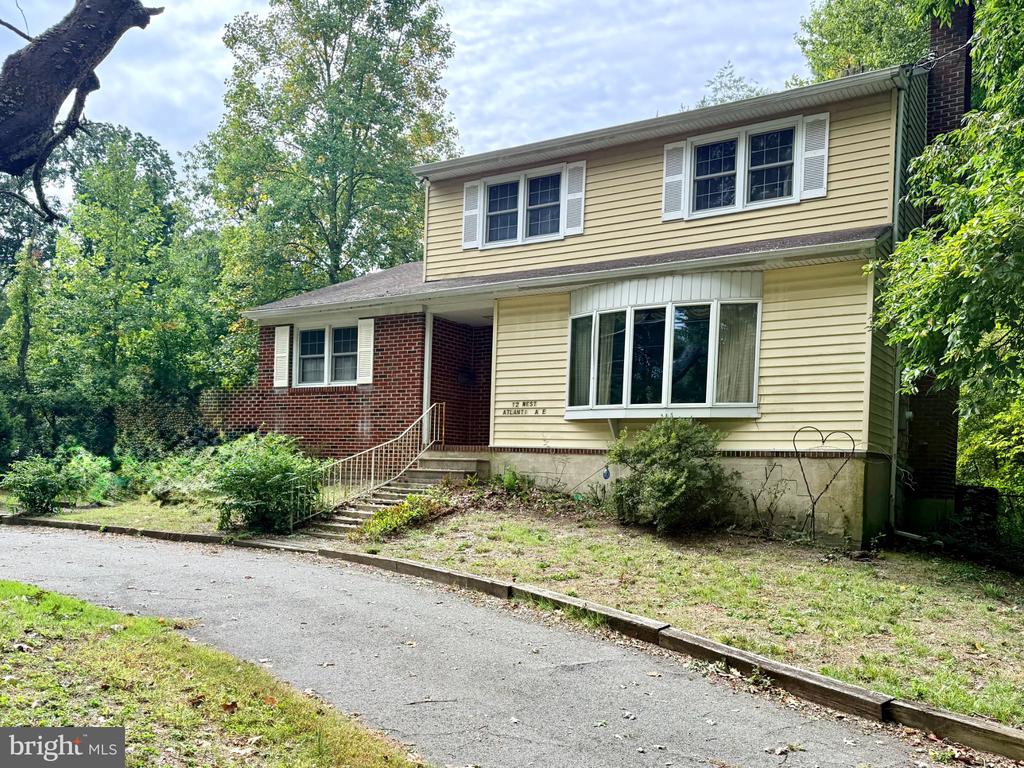 Two-story yellow-sided and red-brick home with a recessed entrance and paved driveway.