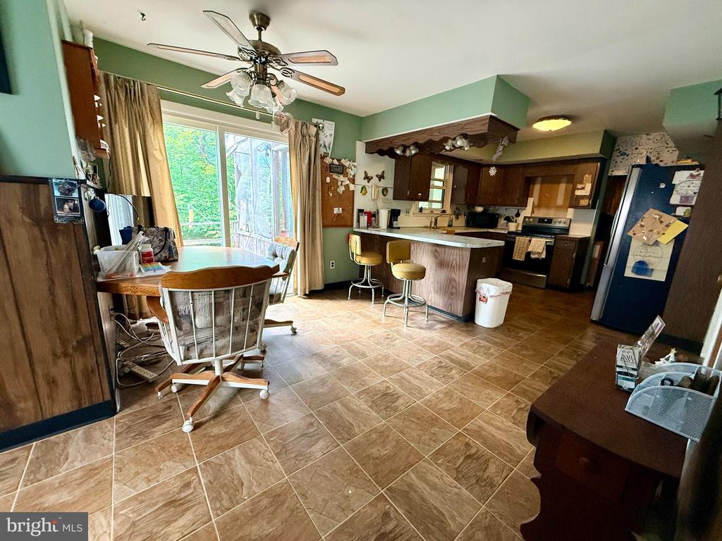 Kitchen with dark wood cabinets, a breakfast peninsula, and dining area by sliding glass doors.