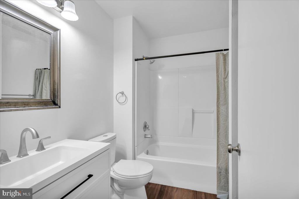 Bathroom with a white vanity, toilet, and bathtub with a patterned shower curtain.