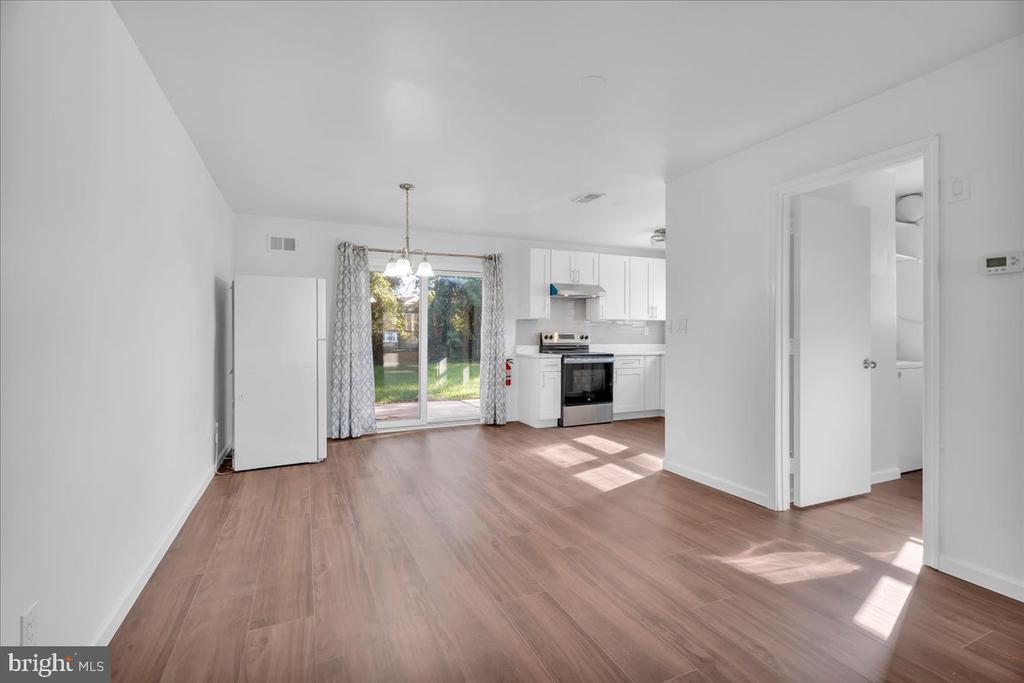 Vacant kitchen and dining area with white cabinets, wood-look floors, and sliding glass doors.