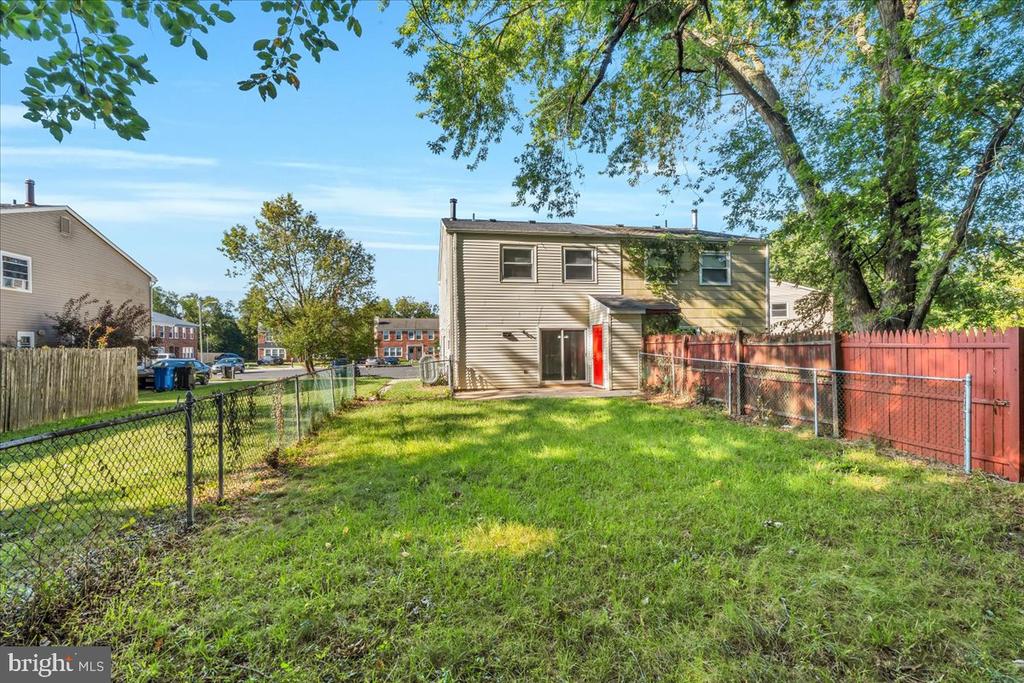 Townhouse rear exterior with a fenced grassy yard and mature trees.