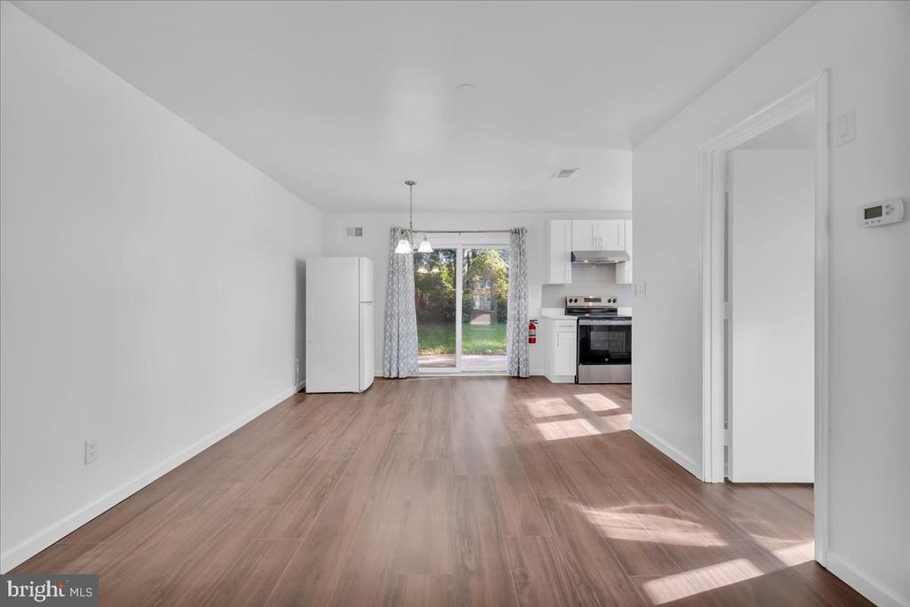 Open kitchen and dining area with wood-look floors, white cabinets, and sliding glass doors.