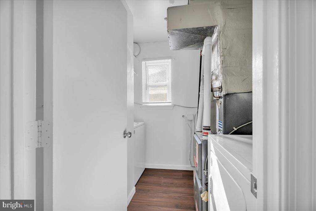 Laundry room with washer and dryer, visible HVAC equipment, and wood-look flooring.