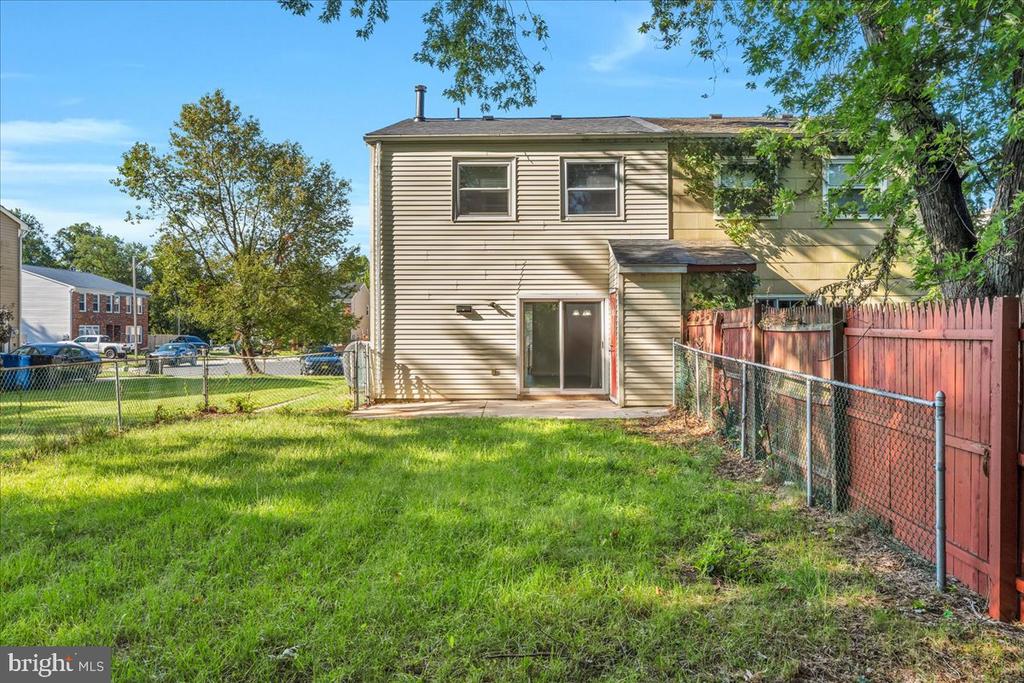 Rear exterior of a two-story home with a fenced grassy backyard and sliding glass door.
