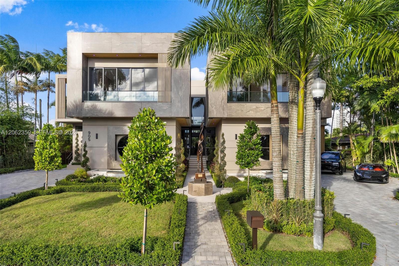 Modern two-story home with glass balconies, tropical palms, and a landscaped front walkway.