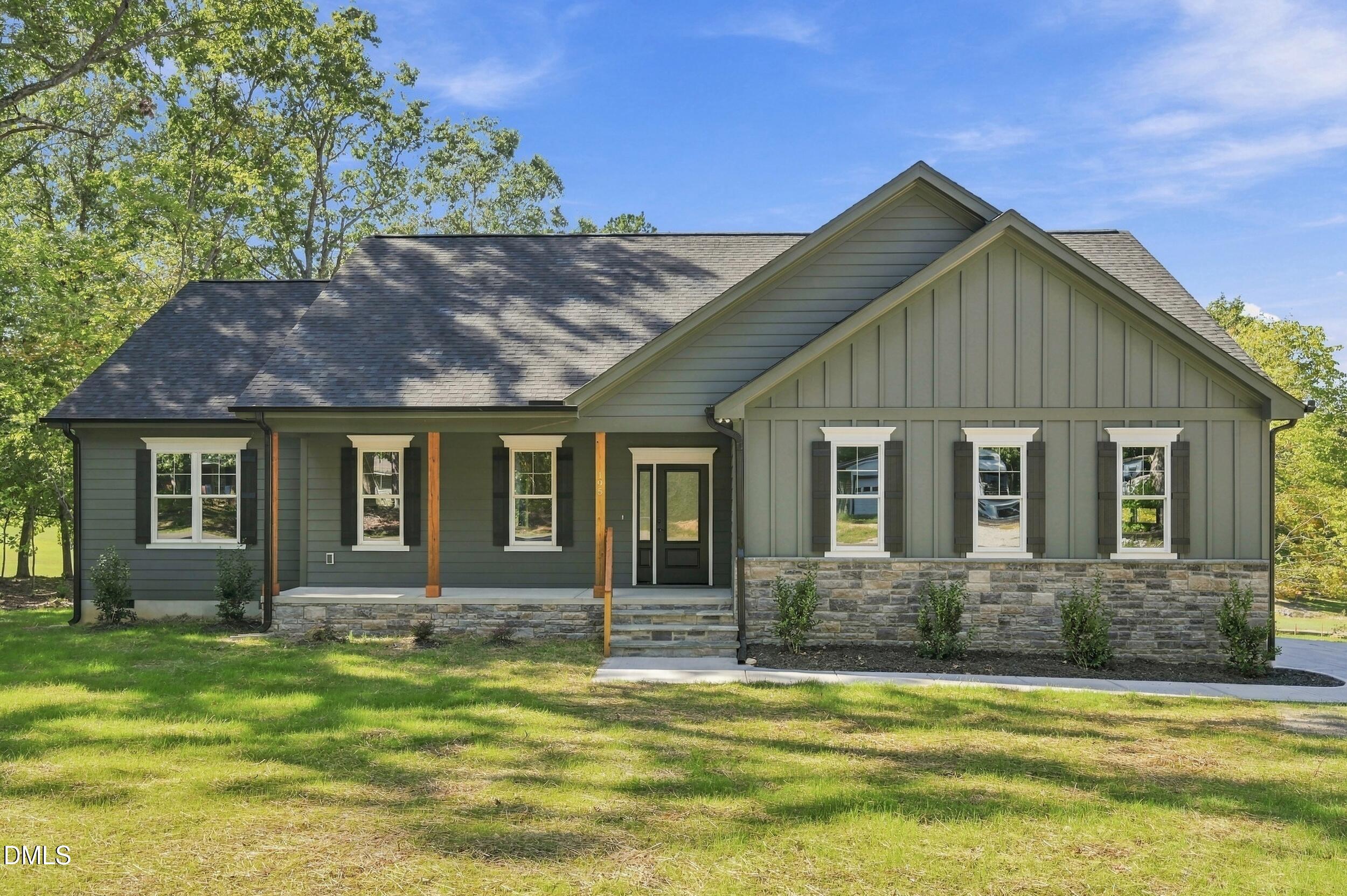 Gray-green single-story house with stone veneer, dark shutters, and a covered front porch.