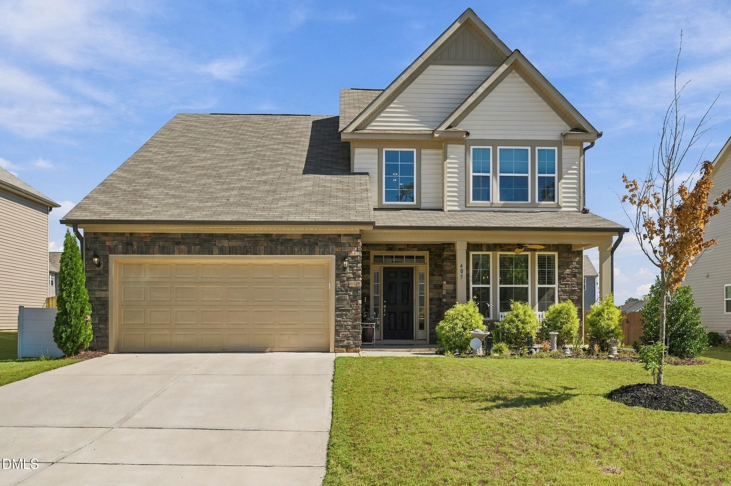 Two-story house with stone facade, steep gables, two-car garage, and landscaped front lawn.