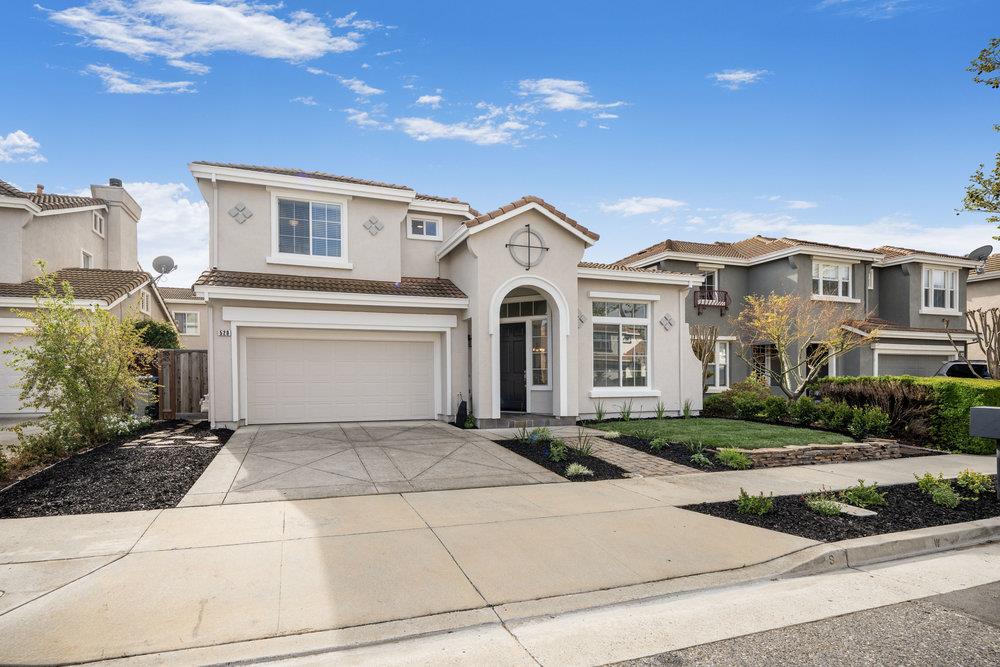 Two-story stucco home with an arched entry, double garage, and landscaped front yard.