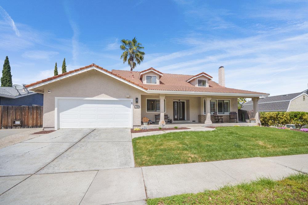 Single-story stucco home with a tile roof, two-car garage, covered porch, and front lawn.
