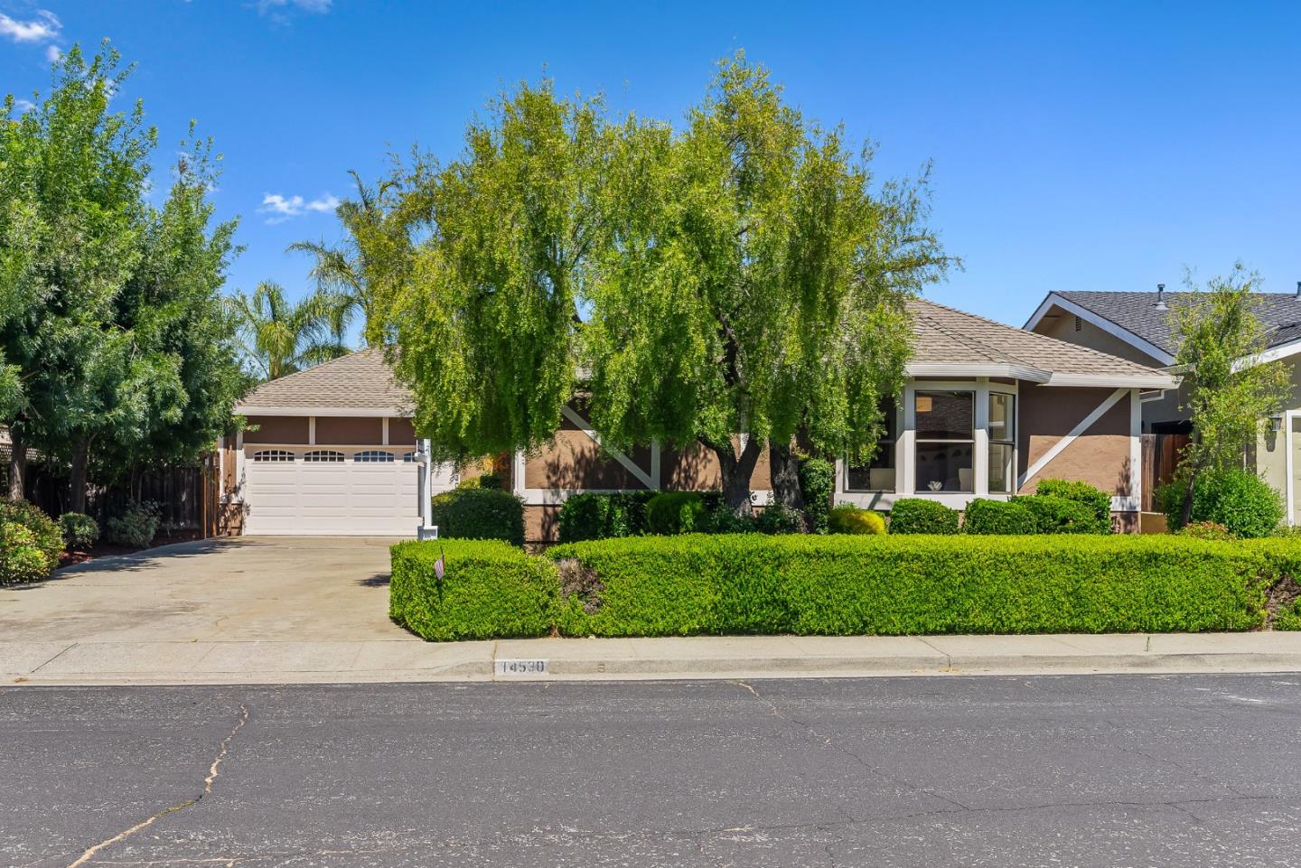 House at 14530 De Anza Court with a white garage, mature trees, and trimmed hedges.
