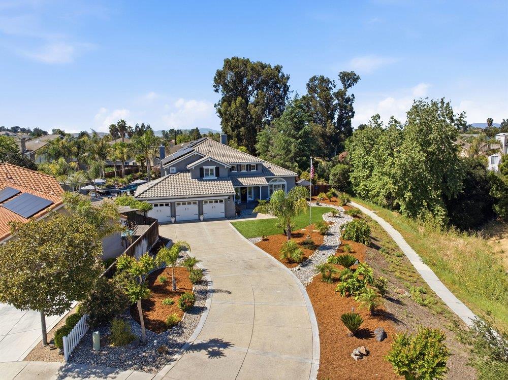 Aerial view of a two-story home with a curved driveway and landscaped front yard.