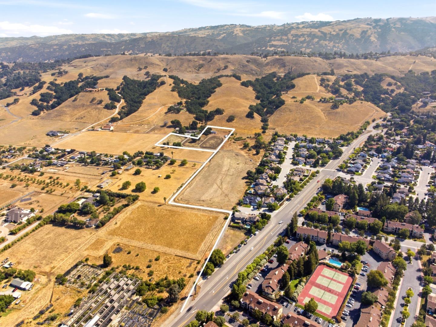Outlined vacant land beside a residential neighborhood, with dry hills and mountains beyond.