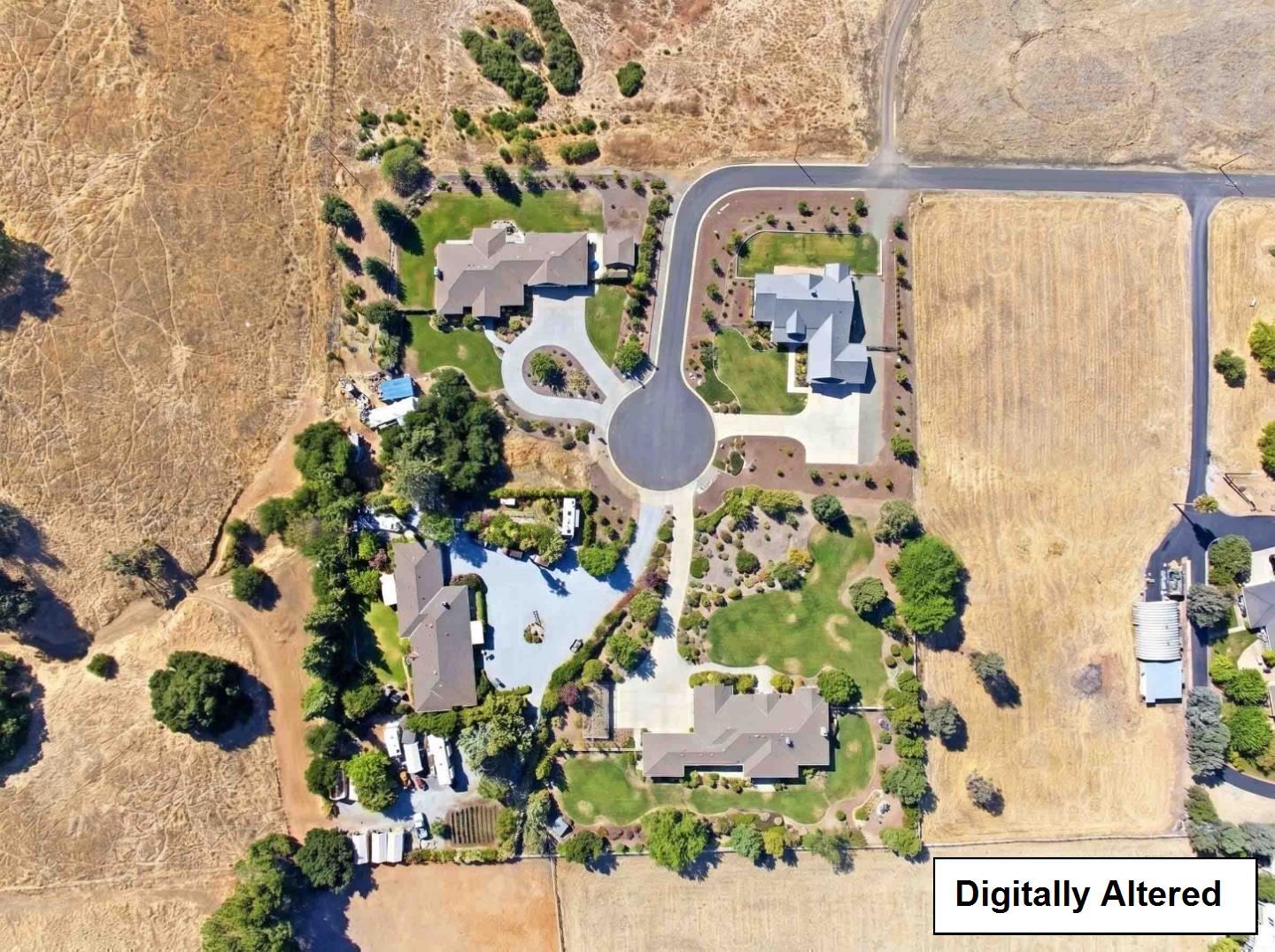 Aerial view of homes around a cul-de-sac, with landscaped yards and dry open fields nearby.