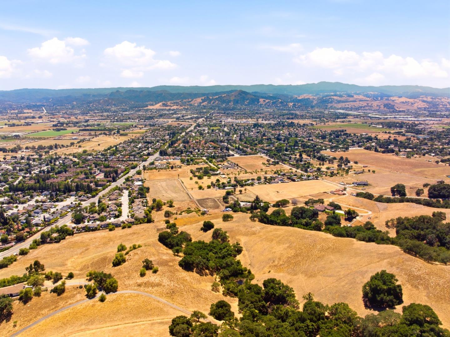 Aerial view of dry open land beside residential neighborhoods, with hills across the horizon.