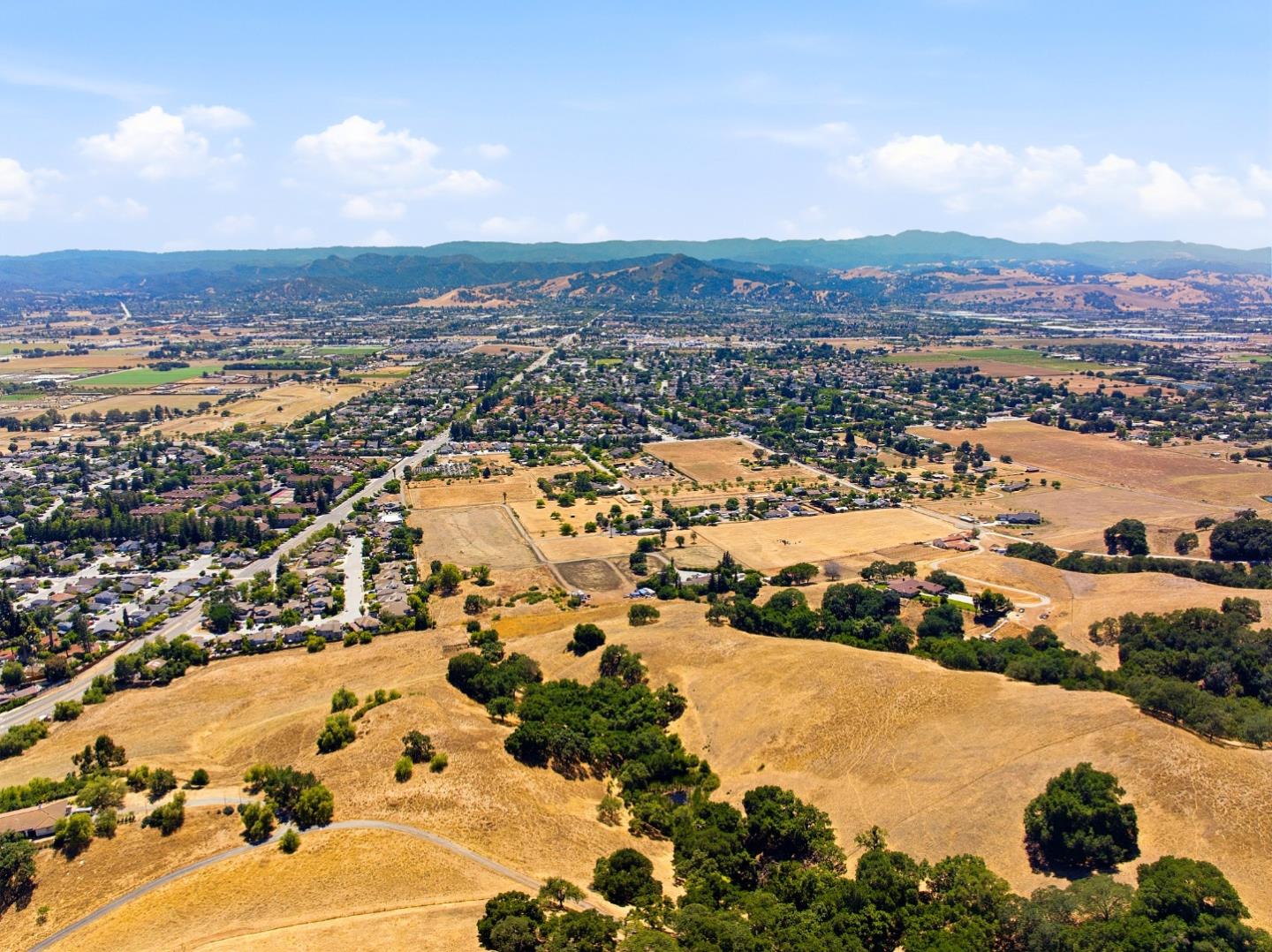 Aerial view of open dry land beside a neighborhood, with distant hills.