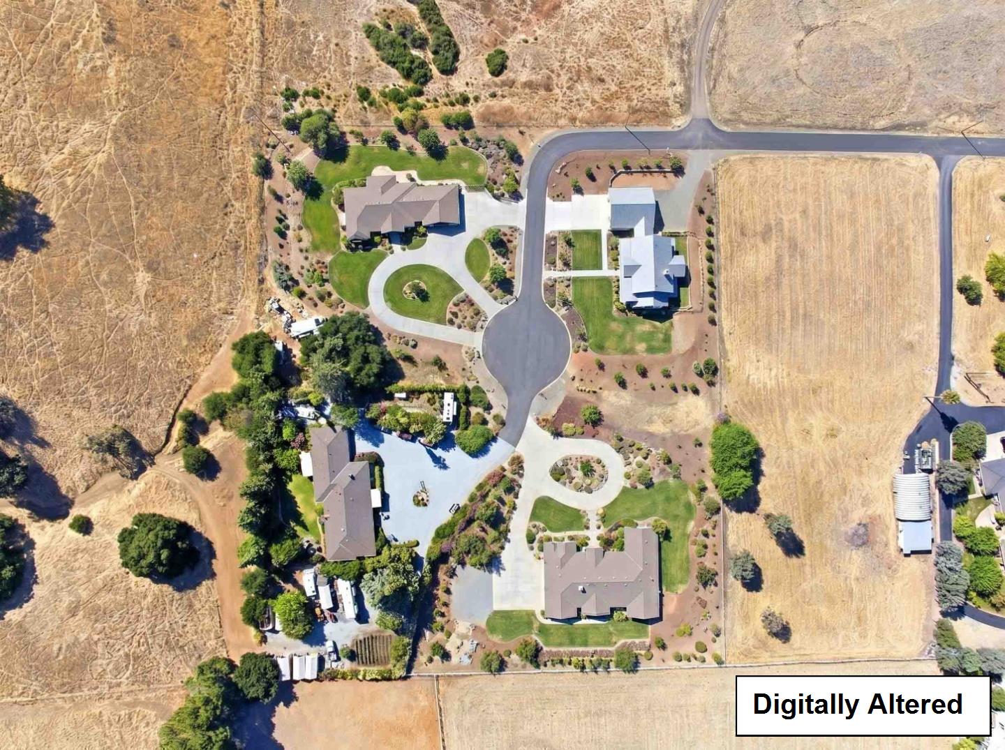 Aerial view of homes with landscaped yards and looping driveways amid dry open fields.