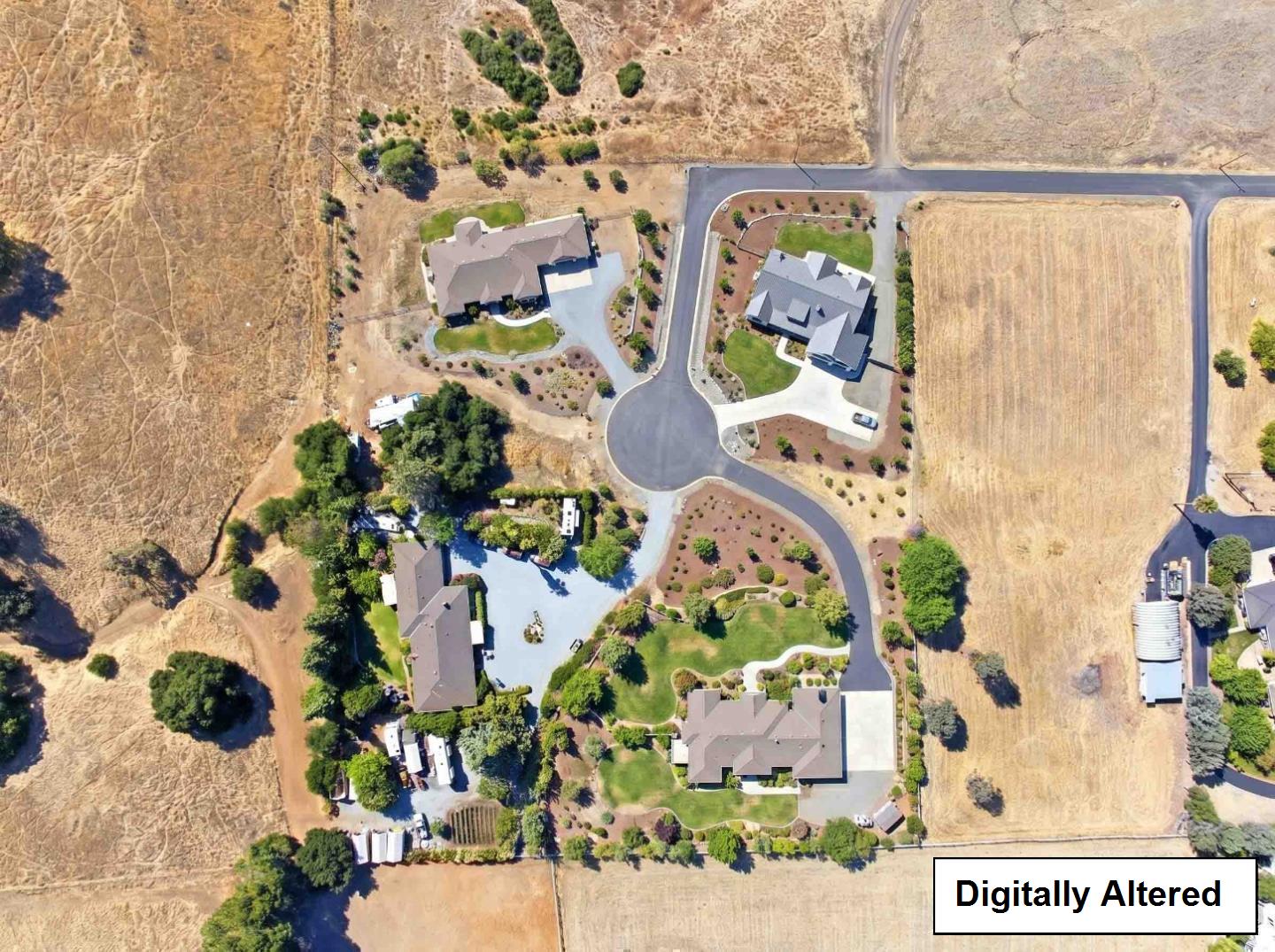 Aerial view of homes along a cul-de-sac, surrounded by dry open fields.