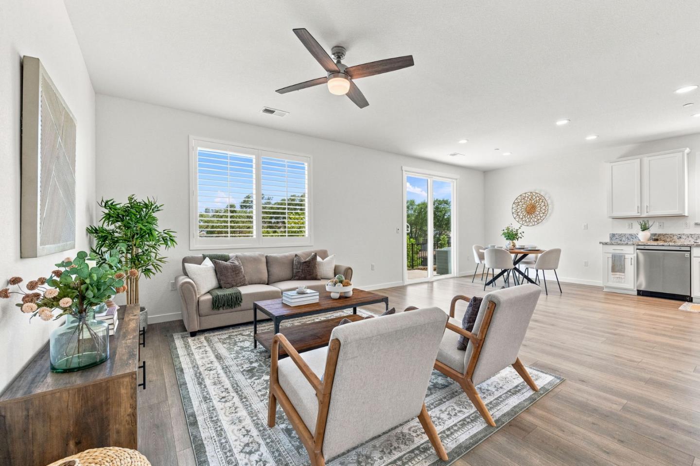 Open-plan living room with a gray sofa, wood coffee table, and dining area beside the kitchen.