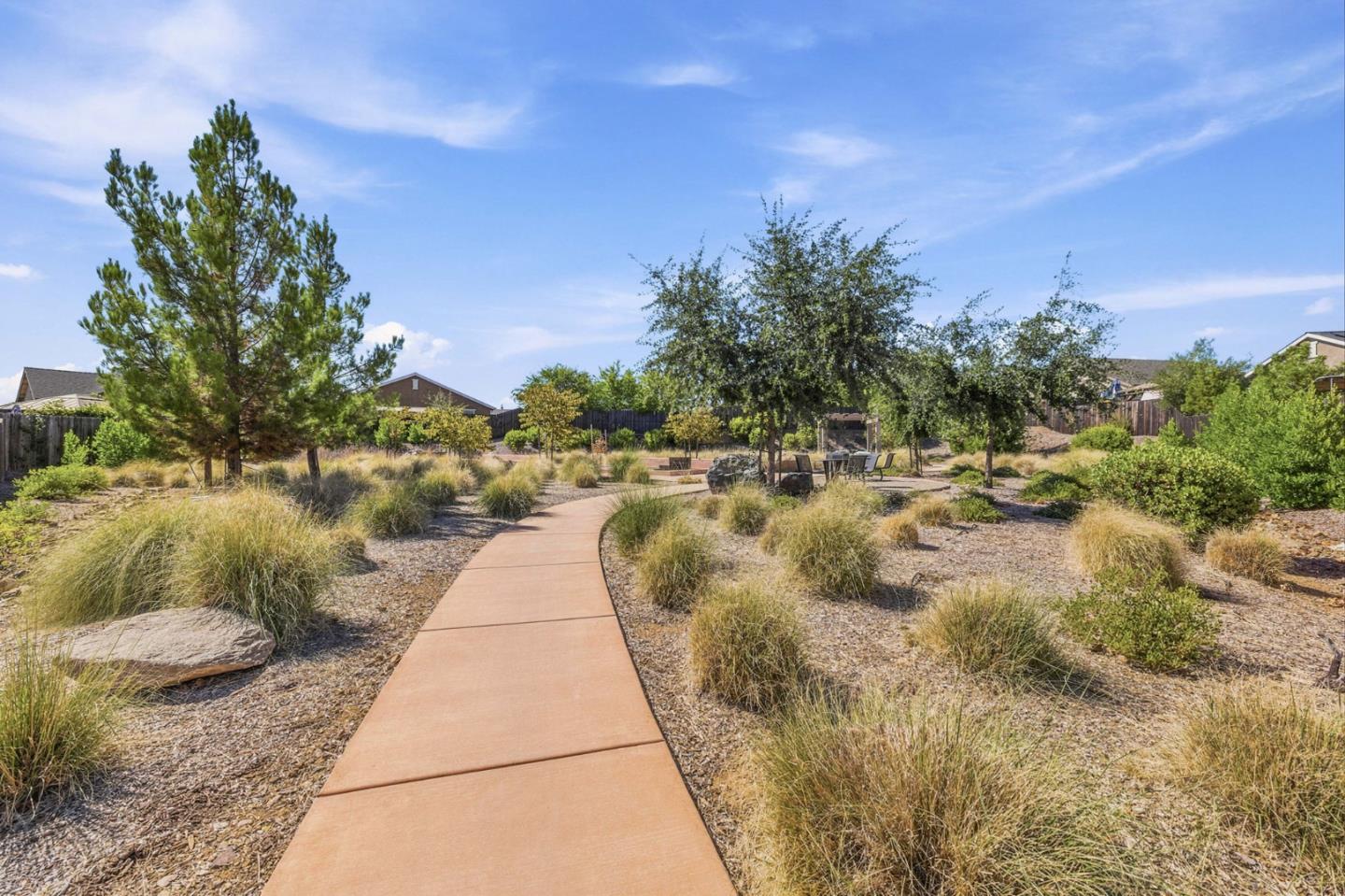 Landscaped yard with a curving walkway leading to an outdoor seating area.