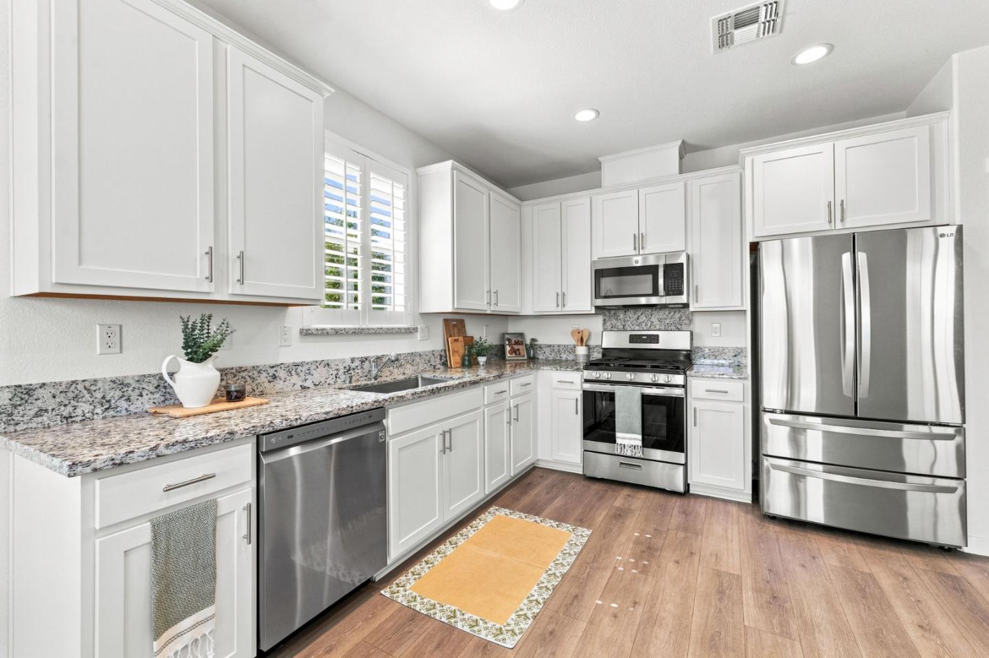 Bright kitchen with white cabinets, granite counters, and stainless steel appliances.