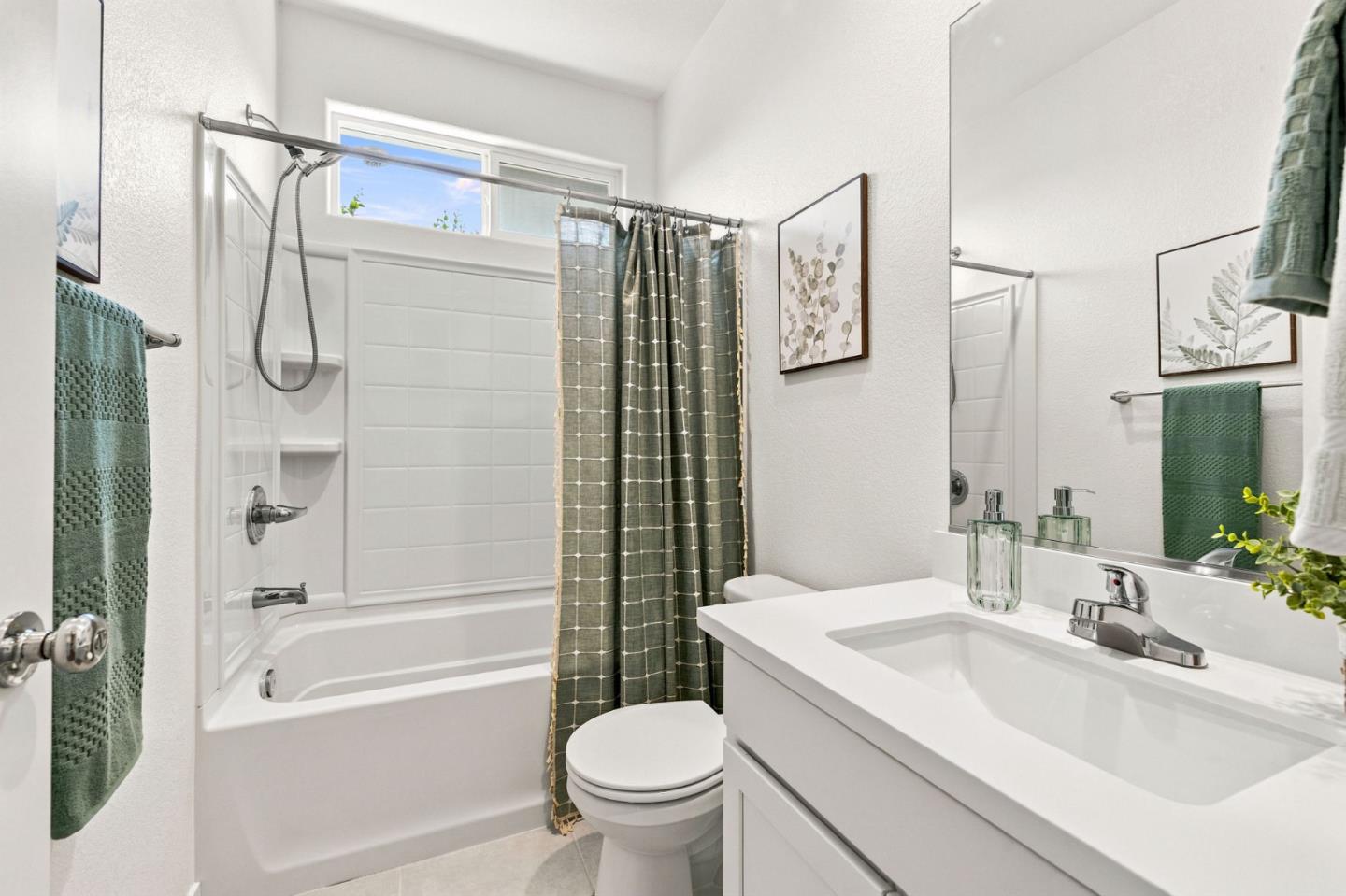 Bathroom with a white tub, green shower curtain, toilet, and vanity with a large mirror.