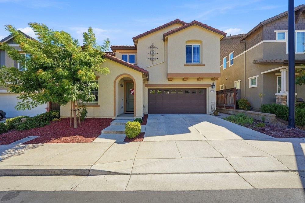 Two-story stucco home with an arched entry, attached garage, and wide driveway.