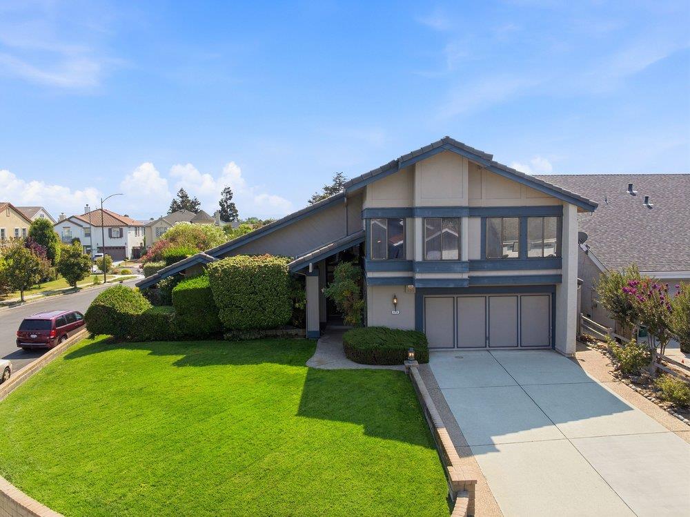 Gray-and-blue house with a broad gabled roof, attached garage, wide driveway, and bright green lawn.