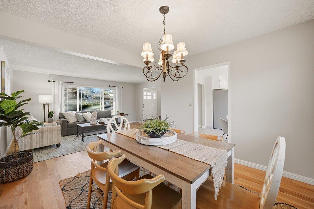 Dining room with a large wood table and chandelier beside a bright living area.