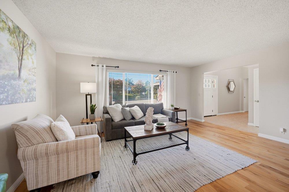 Furnished living room with a gray sofa, striped armchair, and hardwood floors.