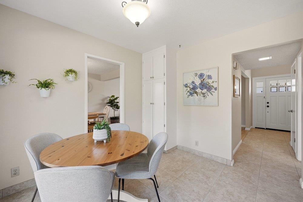Dining area with an oval wooden table, gray chairs, built-in cabinets, and a tiled entryway.