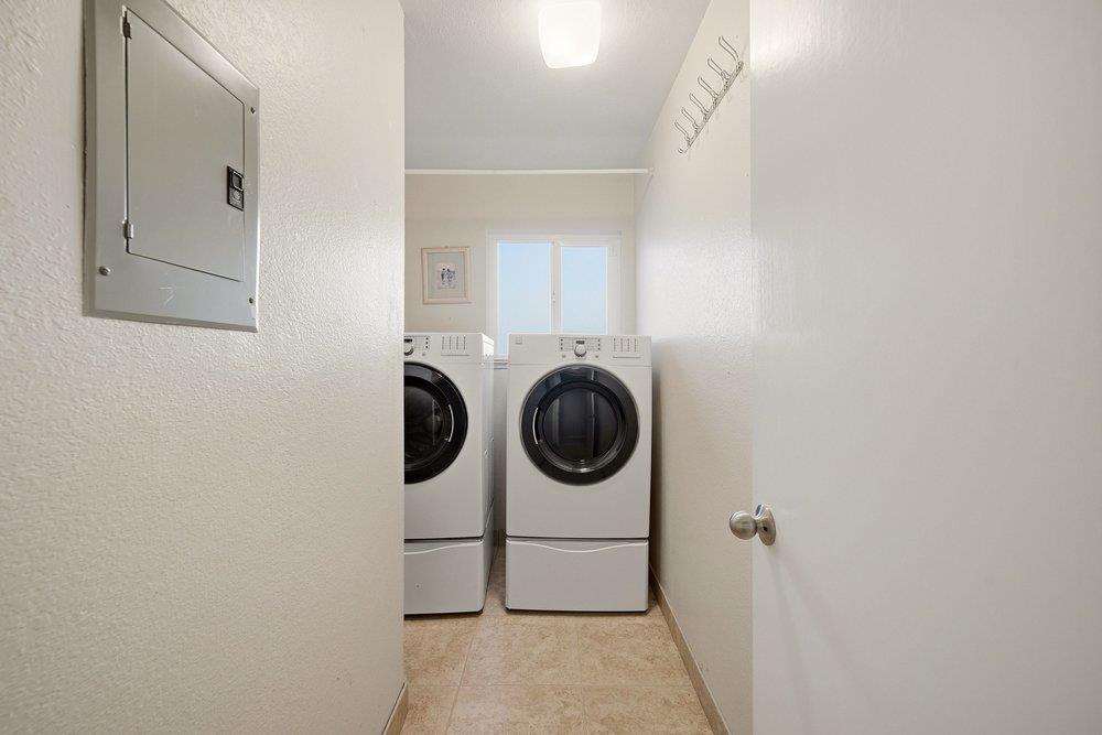 Laundry room with stacked front-loading washer and dryer beneath a window.
