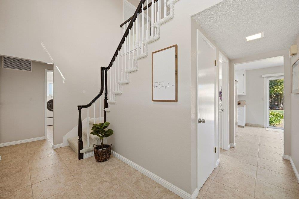 Entryway with tiled floors, a dark-railed staircase, and a hallway opening to a glass exterior door.