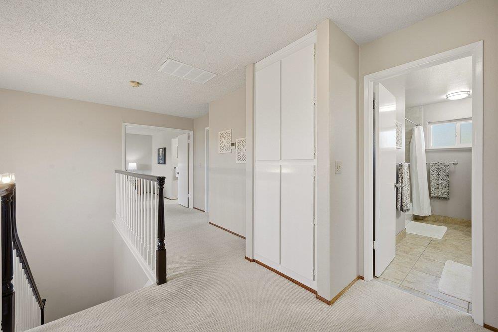 Upstairs hallway with built-in cabinets, stair railing, and an open bathroom doorway.