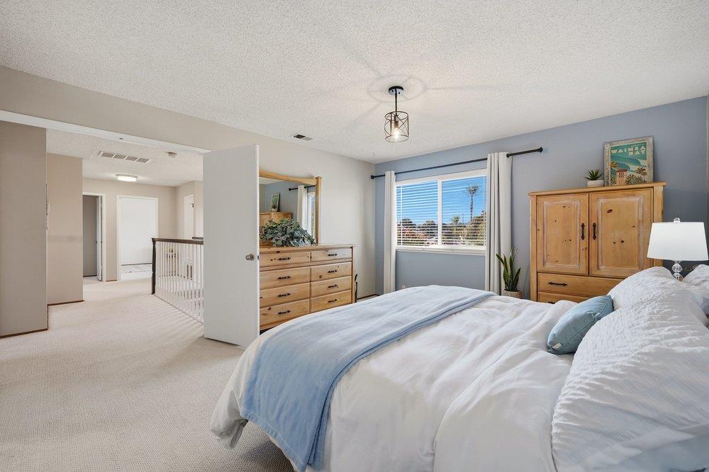 Bedroom with pale blue bedding, light wood furniture, and a window overlooking the neighborhood.