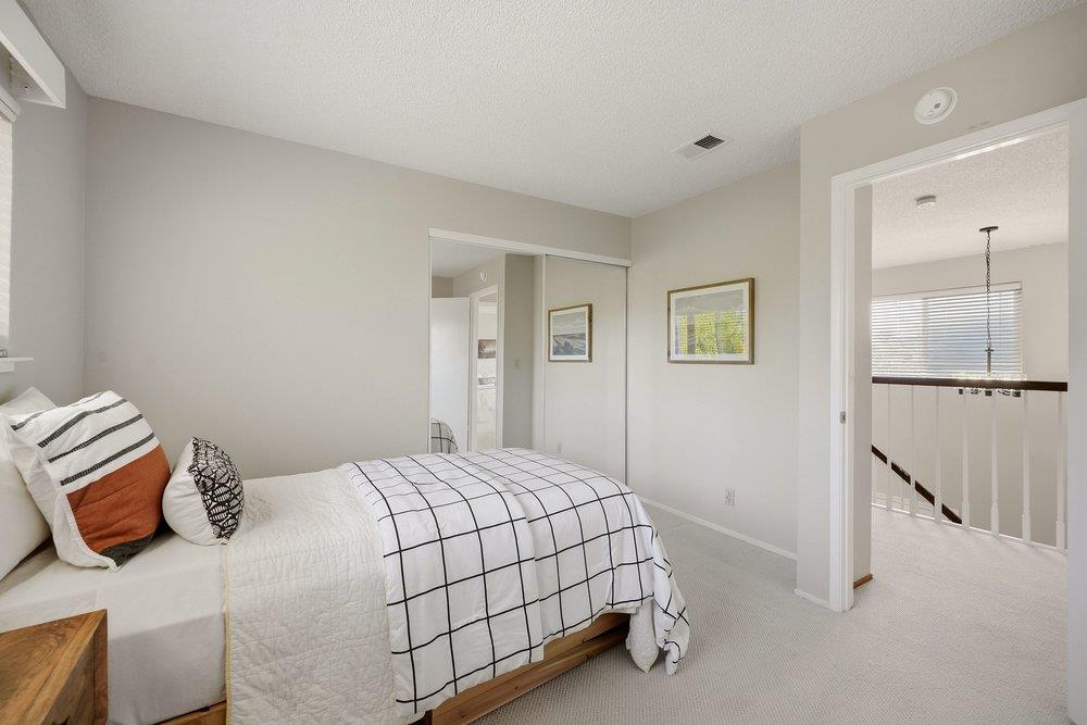 Bedroom with a white grid-patterned bedspread, mirrored closet, and open doorway to the landing.