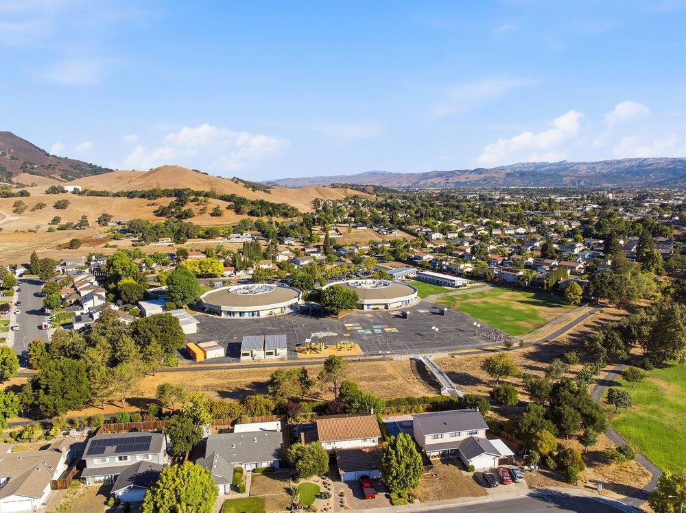 Aerial view of a neighborhood and school campus with dry hills and mountains beyond.