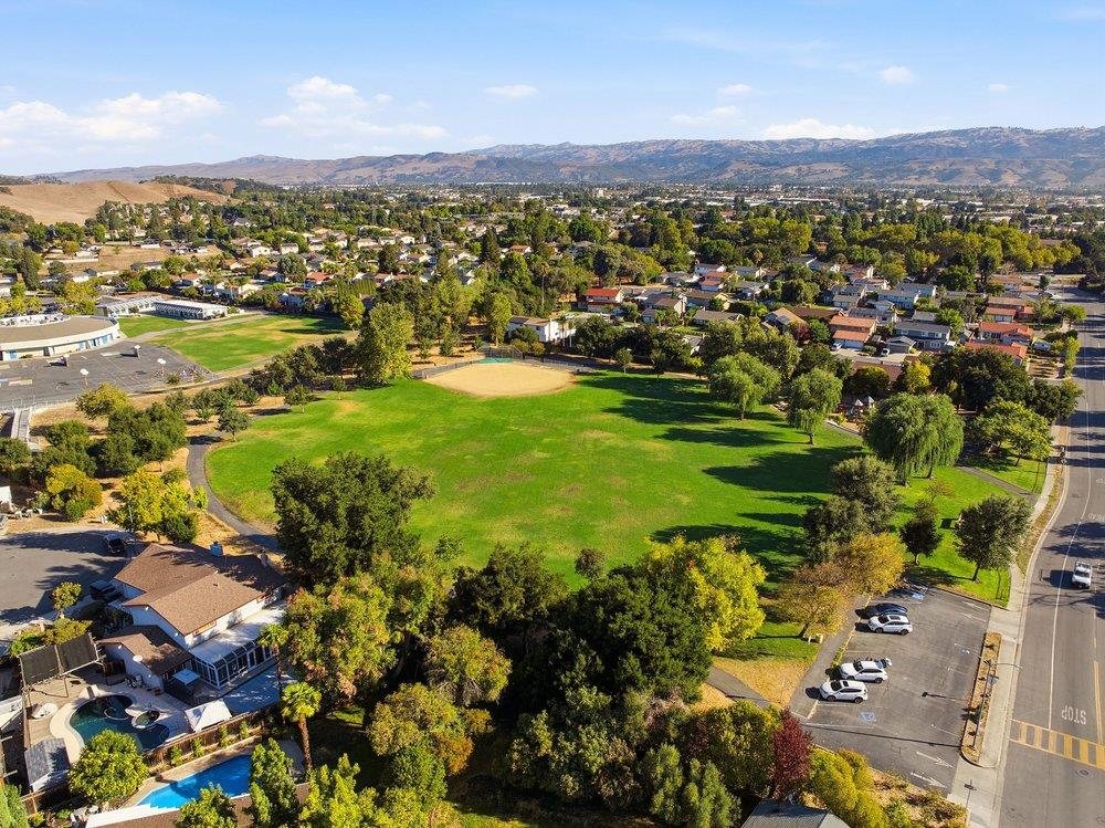 Aerial view of a neighborhood park and baseball field, with homes and hills beyond.