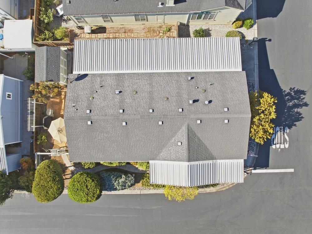 Aerial view of a large gray-roofed property with landscaped shrubs and surrounding streets.