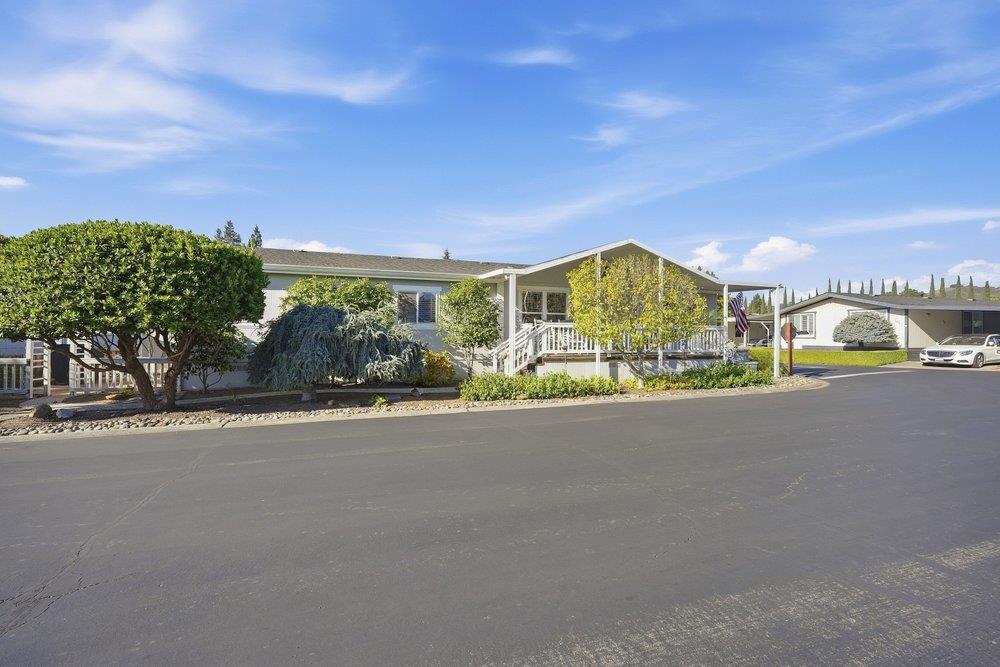 Single-story home with a raised white porch, landscaped front yard, and paved street.